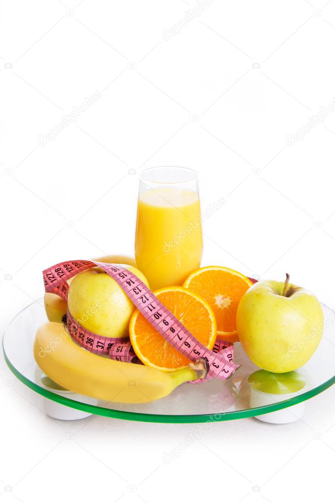 Some fruits, juice and measure tape on scales