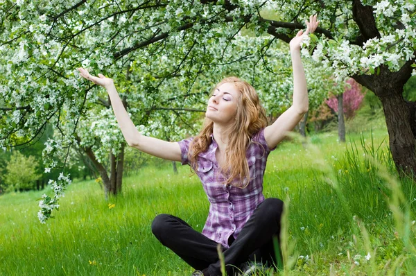 Женщина медитирует под цветущим деревом — стоковое фото