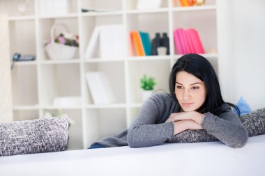 Thoughtful woman sitting on sofa clipart