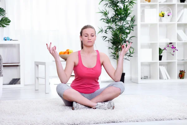 Женщина сидит и медитирует дома — стоковое фото