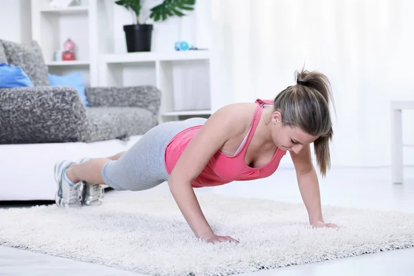 Vrouw kijken neer terwijl het doen van push-ups — Stockfoto