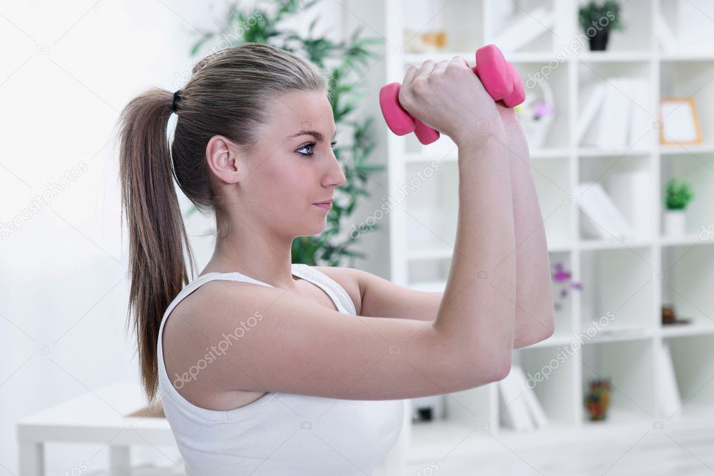 Pretty young woman lifting dumbbells