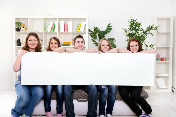 Feliz grupo sorridente de amigos mostrando placa de cartaz em branco — Fotografia de Stock