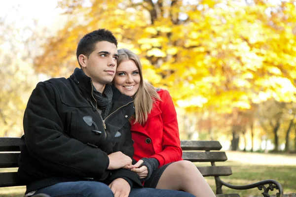 Jovem casal sentado no banco — Fotografia de Stock