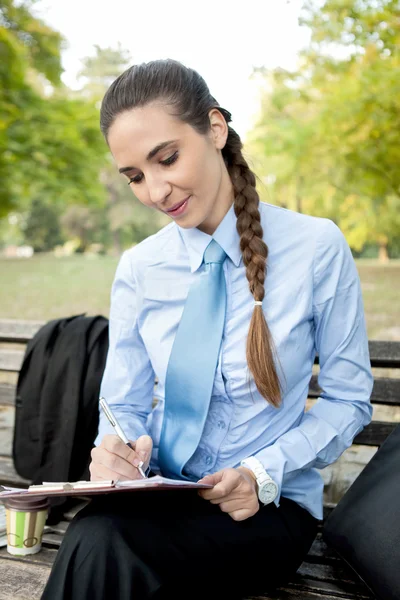 Businesswoman making note in park — Stock Photo, Image