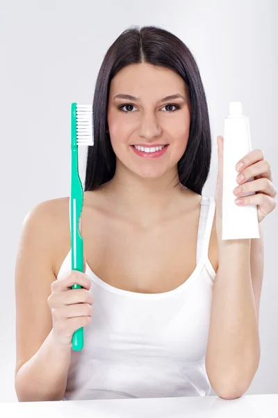 Молодая женщина с зубными щетками и зубной пастой — стоковое фото