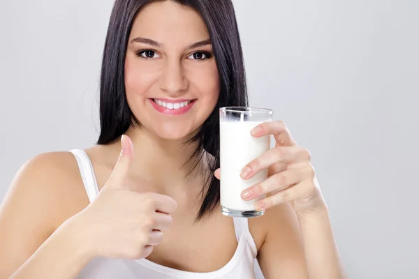 Ragazza con un bicchiere di latte mostrando pollice in su — Foto Stock