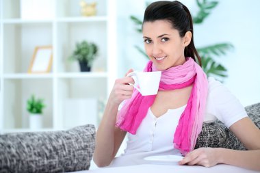 Beauty lady sitting on sofa and drinking coffee clipart