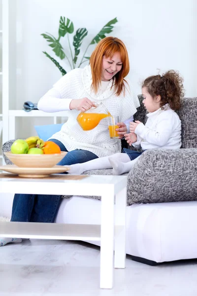 Mãe e filha bebendo suco de laranja — Fotografia de Stock