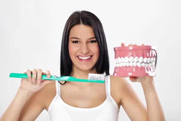 Chica sonriente con mandíbulas y cepillo de dientes —  Fotos de Stock