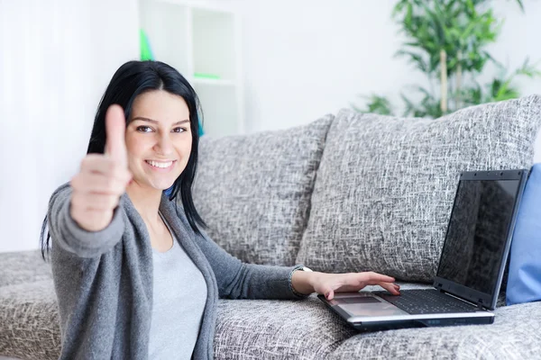 Mujer con portátil mostrando el pulgar hacia arriba en casa — Foto de Stock