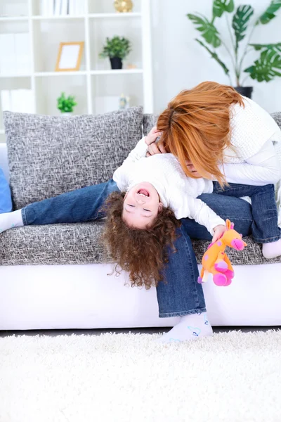 Мама играет со своей дочерью на диване — стоковое фото