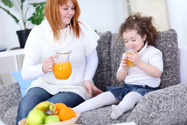 Mãe e filha bebendo suco de laranja — Fotografia de Stock