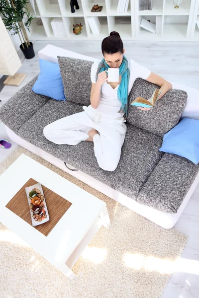 Entspannungsfrau mit Tee und Buch im Wohnzimmer — Stockfoto
