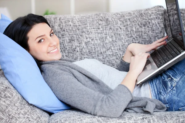 휴대용 퍼스널 컴퓨터와 소파에 누워 여자 — 스톡 사진