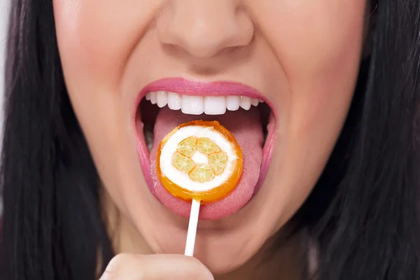 Young girl licking a round colorful lollipop Stock Picture