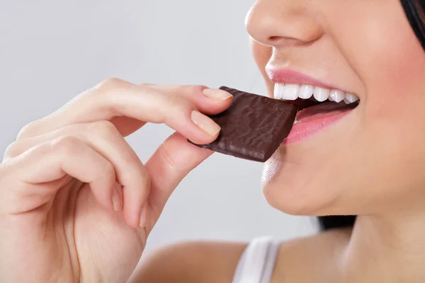 Frau beißt Scheibe der Schokolade lizenzfreie Stockfotos