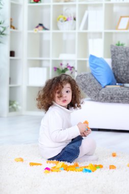 Small girl playing with blocks on floor clipart