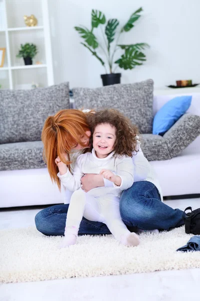 Счастливая молодая мать играет со своей маленькой дочерью — стоковое фото