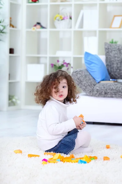 Маленькая девочка играет с блоками на полу — стоковое фото