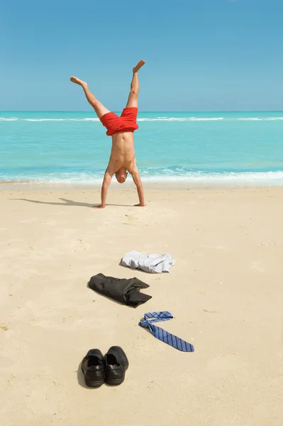 Бизнесмен делает стойку на руках на пляже — стоковое фото