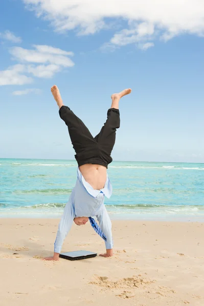 Zakenman doen handstand op het strand — Stockfoto