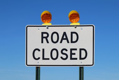 Road closed sign against a bright blue sky clipart