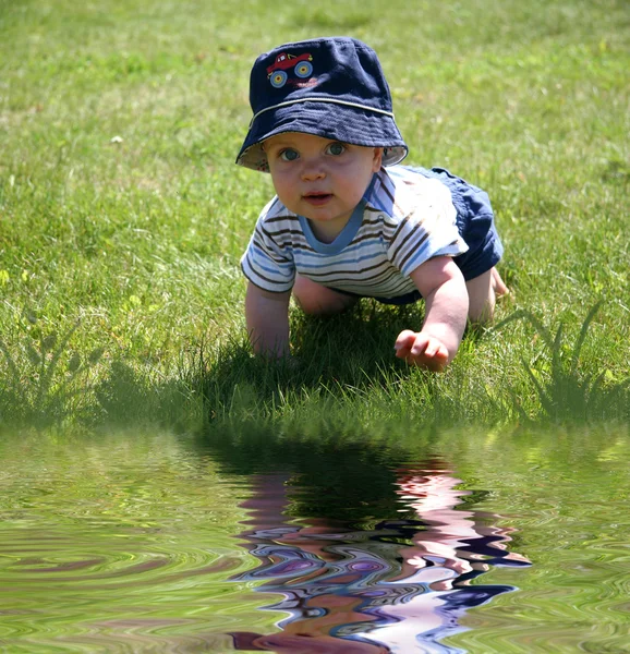 Baby im Gras am Wasser — Stockfoto