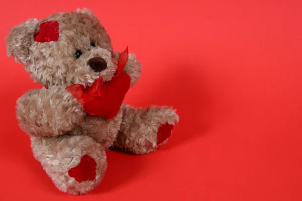 Pequeño oso de peluche sobre fondo rojo —  Fotos de Stock