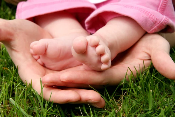 Ręce matki krążyna jej dziecka córka stóp — Zdjęcie stockowe
