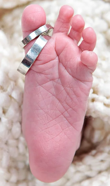 Neonati piede preso primo piano con anelli — Foto Stock