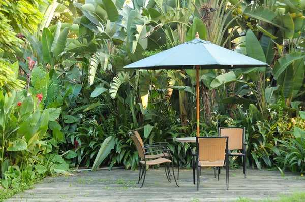 花园家具-藤制椅子和桌子上 w 的保护伞下 — 图库照片