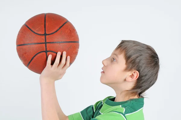 Ein Junge wirft einen Basketball lizenzfreie Stockbilder