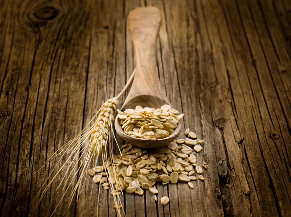 Spoon with oat on wood background — Stock Photo, Image