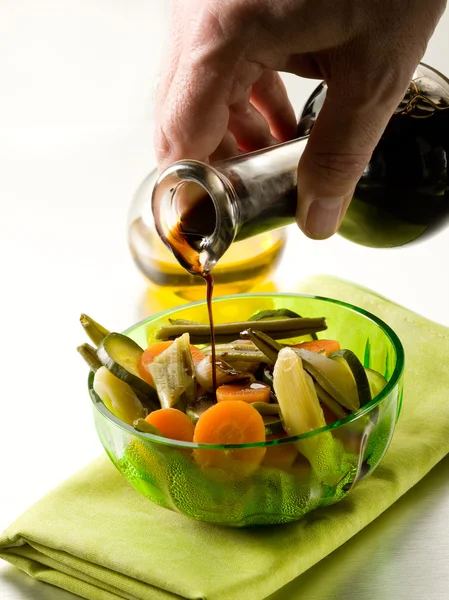 Pouring balsamic vinegar over steamed vegetables salad — Stock Photo, Image