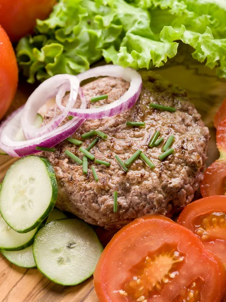 Hambúrguer com legumes de fatia sobre tábua de corte — Fotografia de Stock