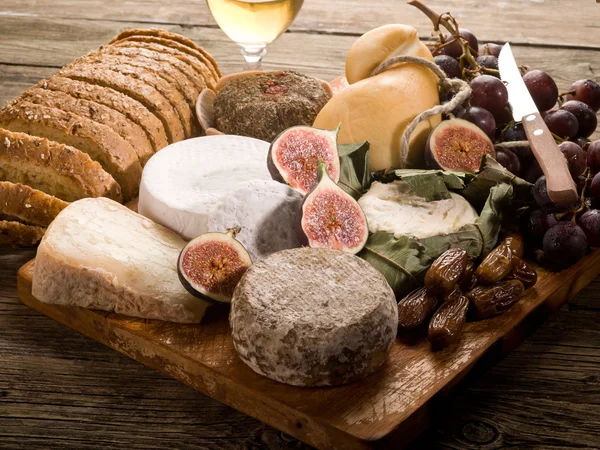 Tagliere con un assortimento di formaggi pane e frutta — Foto Stock