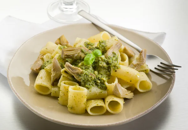 Pasta with pesto and artichoke over steel background — Stock Photo, Image