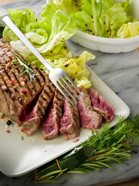 Steak met groene salade gesneden — Stockfoto
