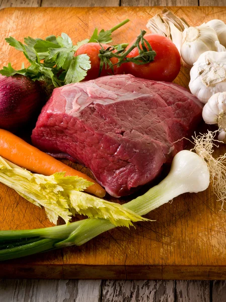 Carne com ingredientes vegetais sobre placa de corte — Fotografia de Stock