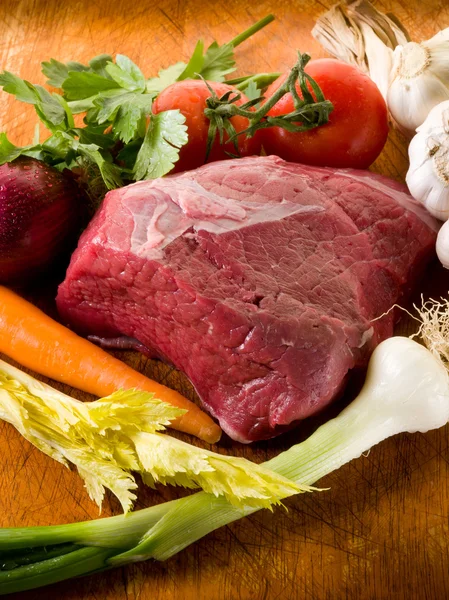 Carne com ingredientes vegetais sobre placa de corte — Fotografia de Stock