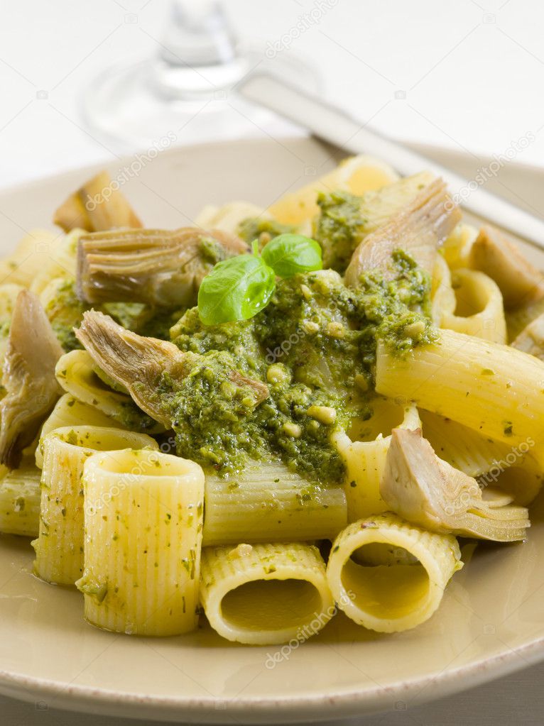 Pasta with pesto and artichoke over steel background