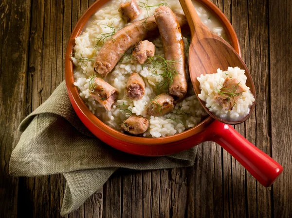 Risotto with sausage over red casserole — Stock Photo, Image