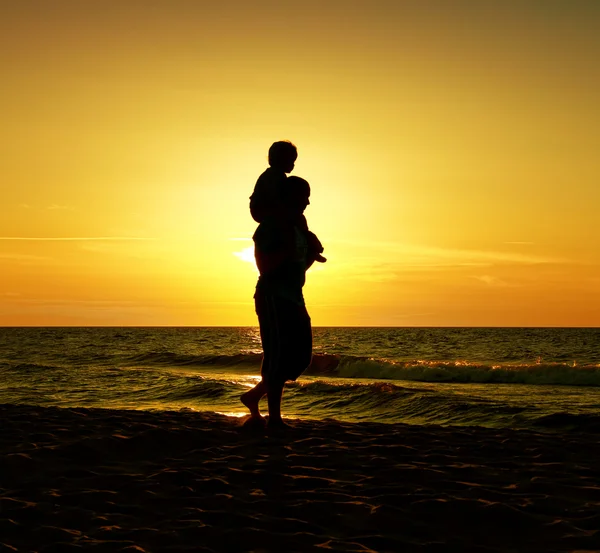 Дитина з батьком у морі на заході сонця — стокове фото