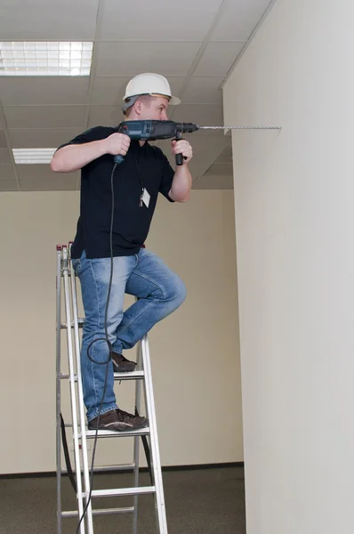 Man op een ladder boren boor — Stockfoto
