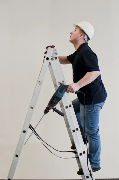 Mann steigt mit Bohrmaschine in Leiter ein — Stockfoto