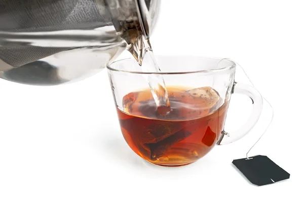 Te från en väska i en glas kopp med en tekanna — Stockfoto