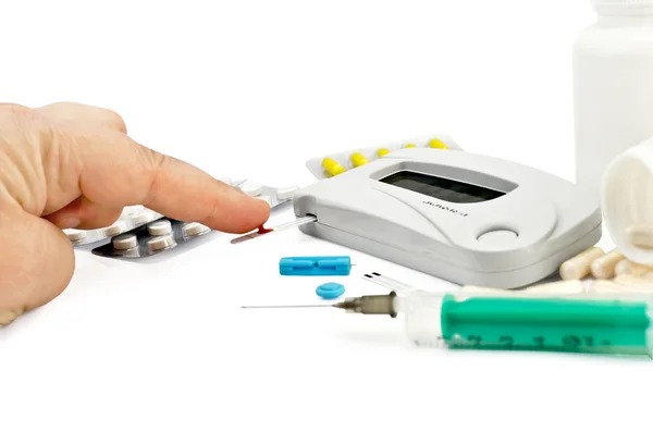 Glucometer with a hand, drugs and a syringe — Stock Photo, Image