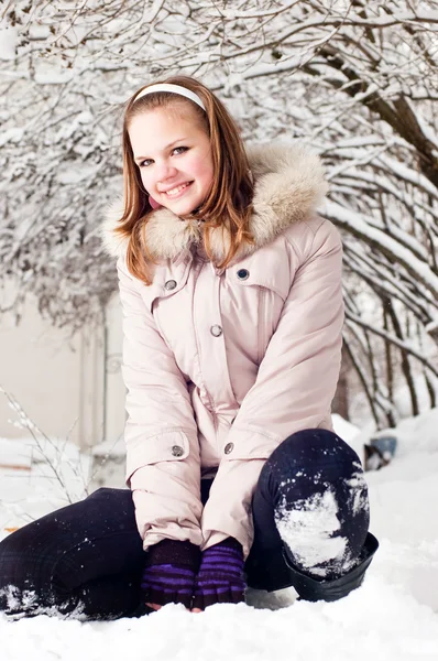 Hermosa joven en una capucha sobre un fondo un árbol nevado — Foto de Stock