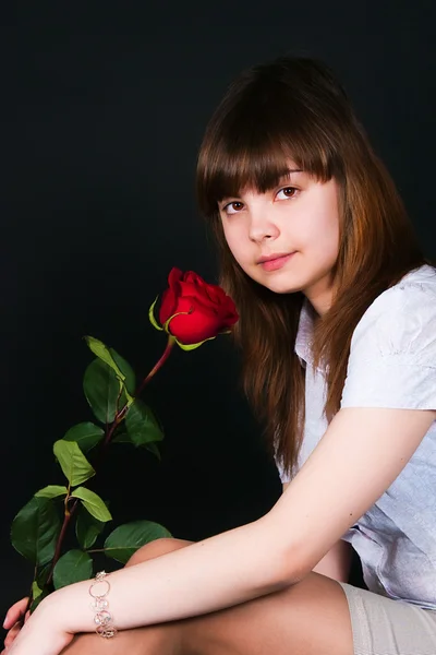 Дівчина з трояндою на чорному тлі — стокове фото